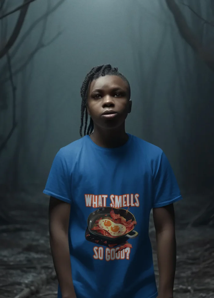 A young boy wearing a soft "What Smells So Good?" t-shirt, smiling and looking carefree.