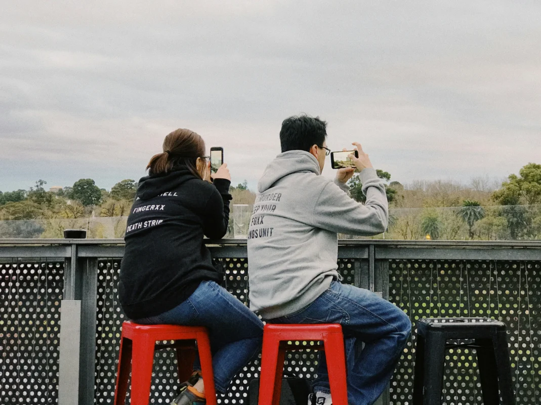 A man and women wearing a black graphic hoodie with a bold logo design, paired with jeans and sneakers.