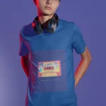 Boy wearing a Cassette Memories t-shirt with a vintage cassette tape graphic, standing outdoors.