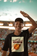 Boy wearing a blue practice basketball t-shirt, dribbling a basketball on an outdoor court.